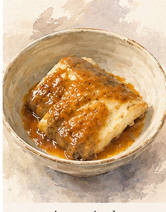 白味噌のマリネに漬けられた銀だらのフィレ。小皿の上に置かれ、焼き上がった深い褐色バージョンが横に添えられている